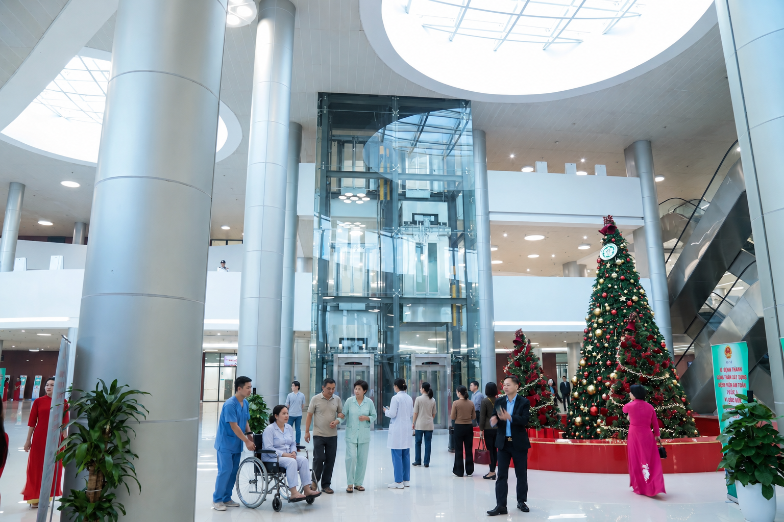 Sảnh bệnh viện hiện đại trang trí cây thông Noel lớn, bệnh nhân ngồi xe lăn và bác sĩ y tá di chuyển quanh thang máy kính